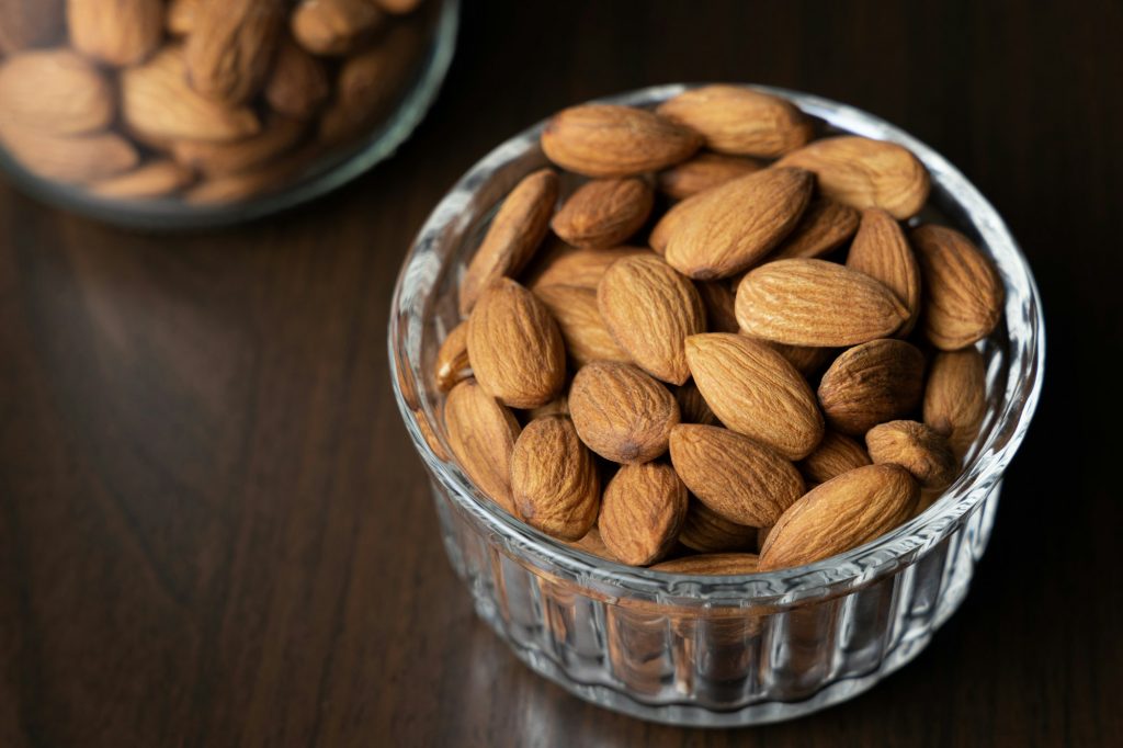 Pile of peeled raw almonds in a bowl on a wooden table